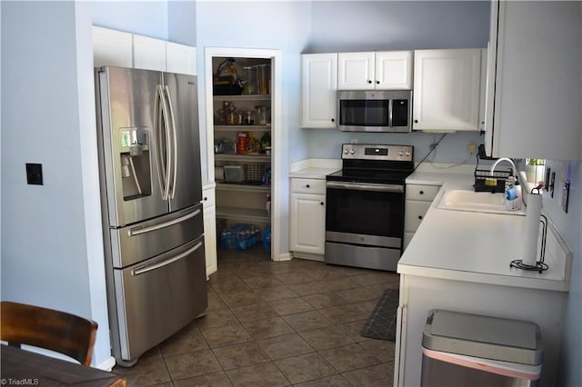 1030 Still Point Dr, Winston-Salem, NC 27103 - kitchen with stainless steel appliances, a sink, light countertops, dark tile patterned floors, and white cabinetry