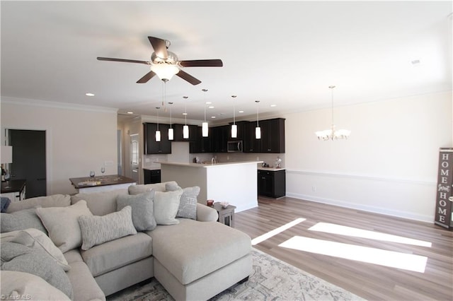 living room with ornamental molding, light hardwood / wood-style flooring, and ceiling fan with notable chandelier