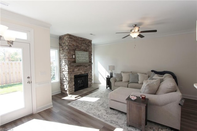 living room with a wealth of natural light, a stone fireplace, dark hardwood / wood-style flooring, and ceiling fan