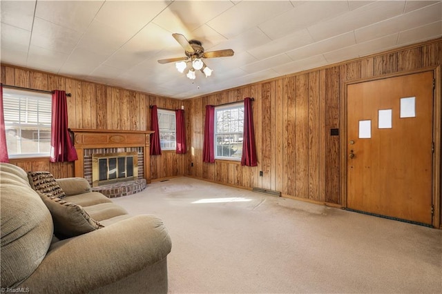 living room featuring ceiling fan, wood walls, carpet floors, and a fireplace