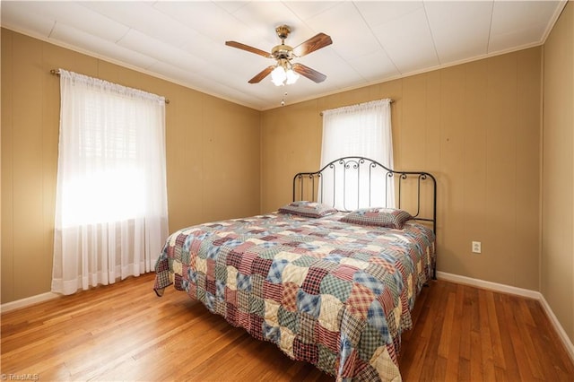 bedroom featuring hardwood / wood-style flooring, ceiling fan, and crown molding