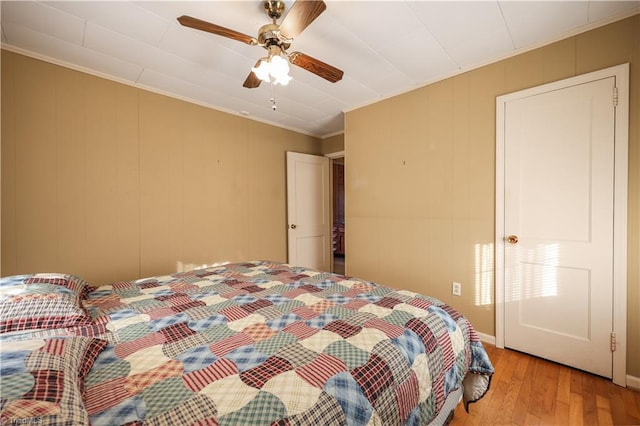 bedroom with light hardwood / wood-style floors, ceiling fan, and crown molding