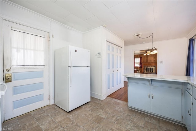 kitchen featuring kitchen peninsula, crown molding, a notable chandelier, white fridge, and hanging light fixtures