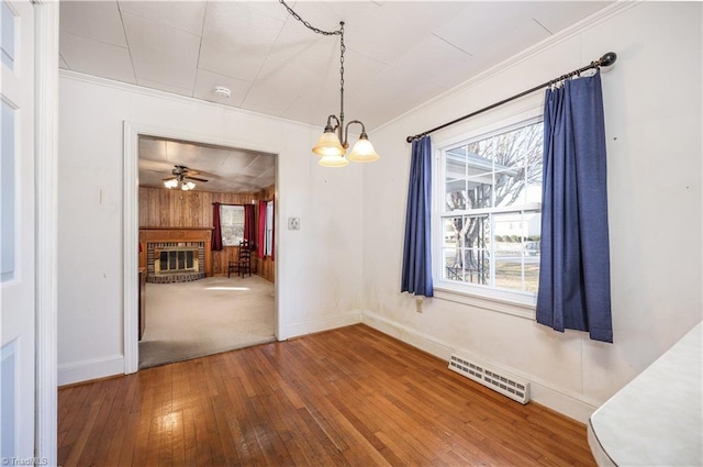 unfurnished dining area with hardwood / wood-style flooring, plenty of natural light, a fireplace, and wooden walls