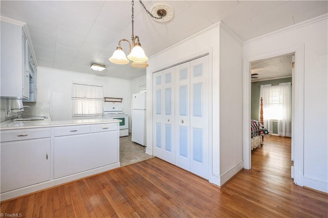 kitchen with sink, hanging light fixtures, an inviting chandelier, hardwood / wood-style floors, and white appliances