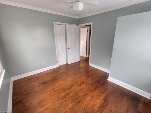 unfurnished bedroom with ornamental molding, dark wood-type flooring, ceiling fan, and a closet