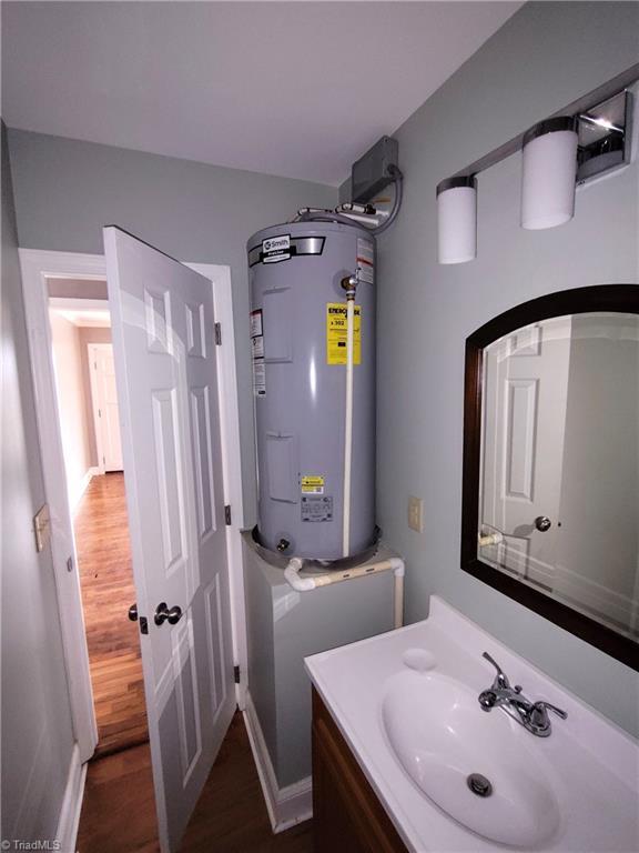 bathroom featuring hardwood / wood-style flooring, vanity, and electric water heater