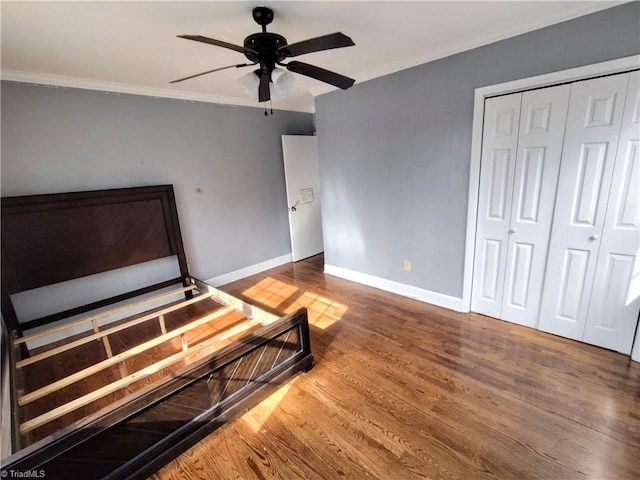 bedroom featuring hardwood / wood-style flooring, ornamental molding, a closet, and ceiling fan