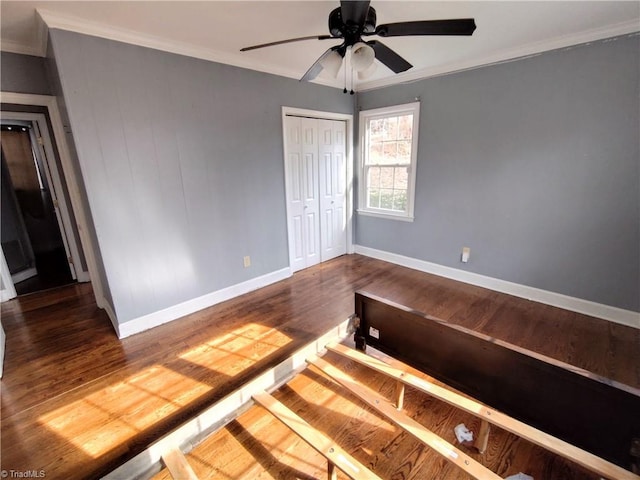 unfurnished bedroom featuring crown molding, dark wood-type flooring, a closet, and ceiling fan