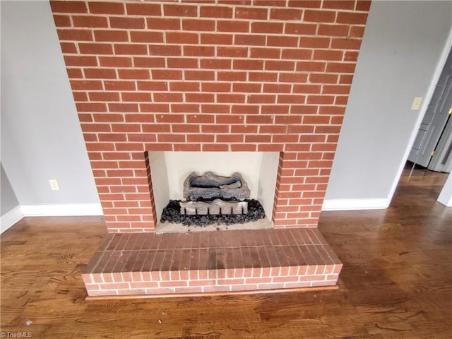 interior details featuring wood-type flooring and a brick fireplace