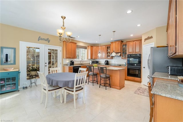 kitchen featuring french doors, hanging light fixtures, a kitchen breakfast bar, a kitchen island, and black appliances