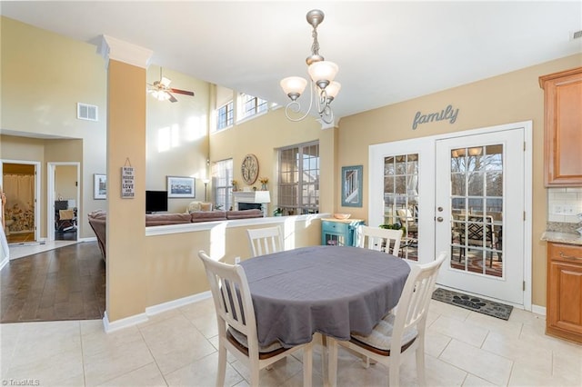 dining area with french doors, light tile patterned flooring, and ceiling fan with notable chandelier