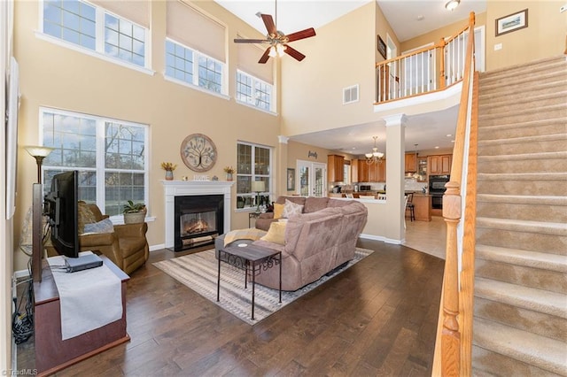 living room with a high ceiling, ceiling fan, and dark wood-type flooring