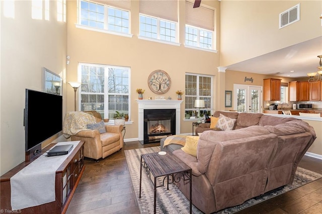 living room with ceiling fan, dark hardwood / wood-style flooring, and a towering ceiling