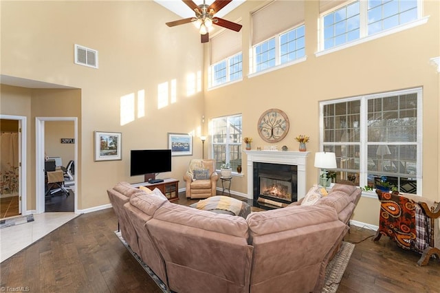 living room featuring ceiling fan, dark hardwood / wood-style flooring, and a towering ceiling