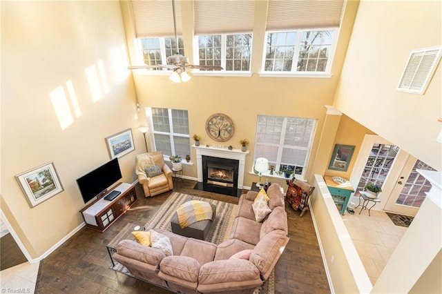 living room featuring hardwood / wood-style floors, ceiling fan, and a towering ceiling