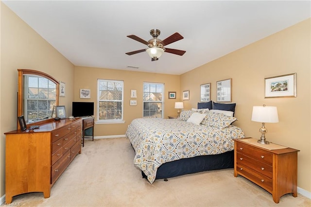 bedroom featuring ceiling fan, light colored carpet, and multiple windows