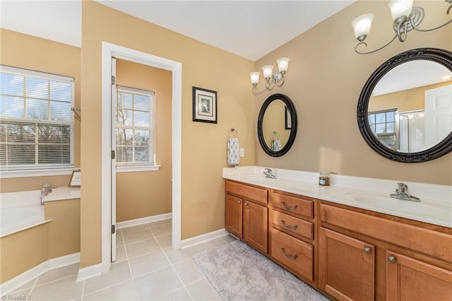 bathroom with a chandelier, vanity, tile patterned floors, and a bathing tub