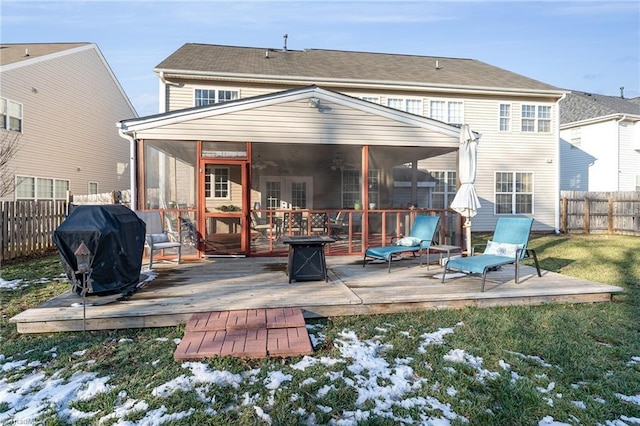 snow covered rear of property with a lawn, a sunroom, and a deck