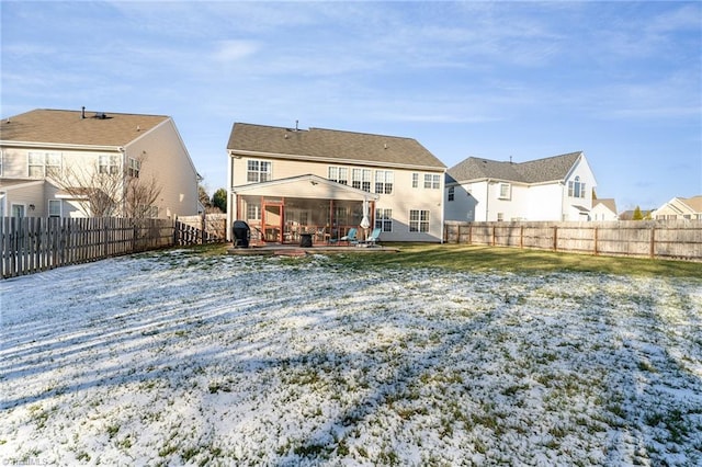 snow covered back of property with a patio area and a lawn