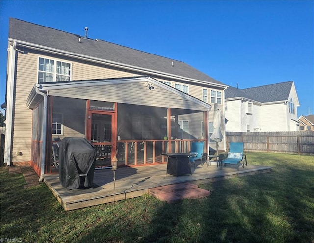 rear view of property featuring a lawn, a wooden deck, and a sunroom