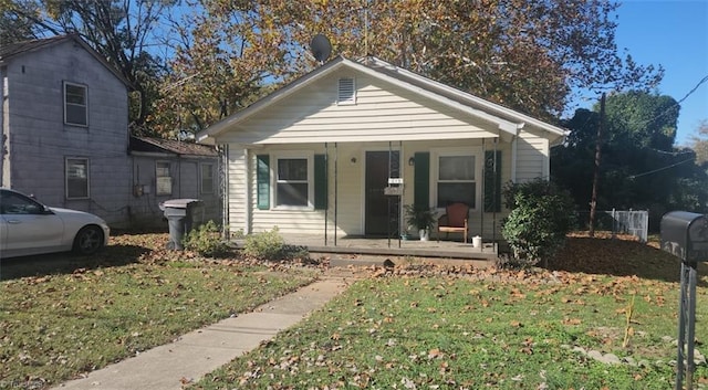 bungalow-style house featuring covered porch and a front yard