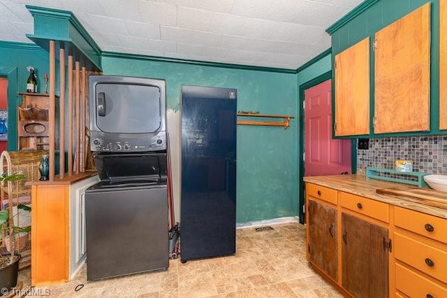 kitchen with stacked washing maching and dryer, decorative backsplash, ornamental molding, and wooden counters