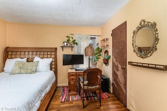 bedroom with dark hardwood / wood-style flooring and ornamental molding