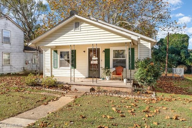 bungalow featuring covered porch and a front yard