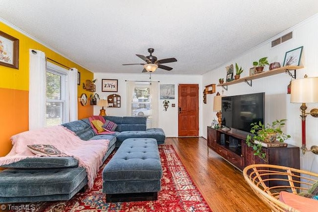 living room with hardwood / wood-style floors, ceiling fan, a textured ceiling, and ornamental molding