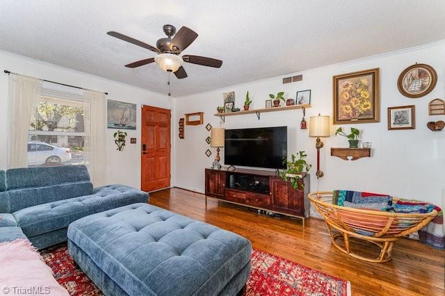 living room featuring wood-type flooring, ceiling fan, and crown molding