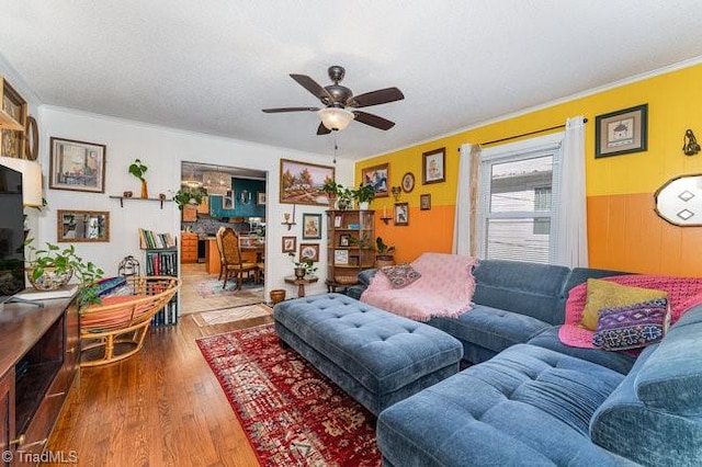 living room featuring hardwood / wood-style flooring, ceiling fan, and ornamental molding