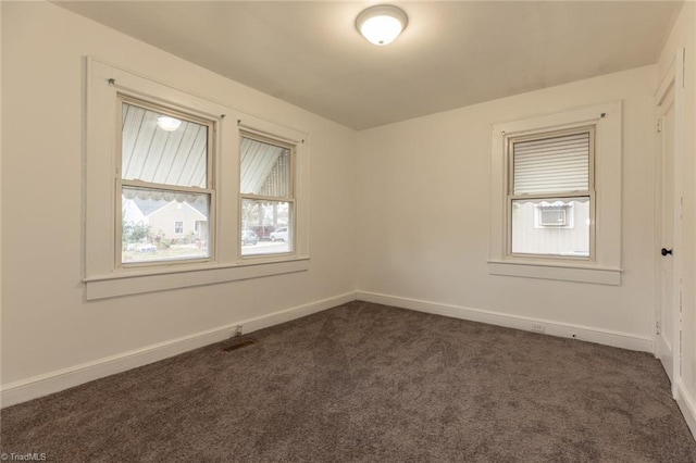 unfurnished room featuring dark colored carpet and baseboards