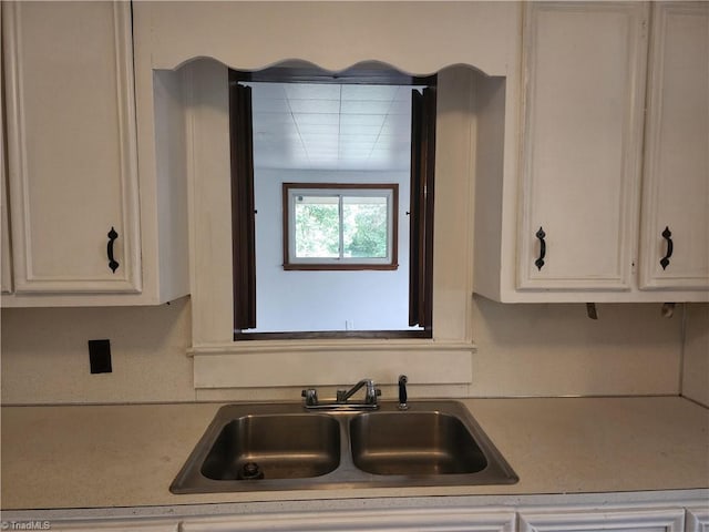 kitchen featuring light countertops, white cabinets, and a sink