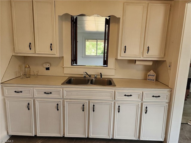 kitchen featuring white cabinetry, light countertops, and a sink