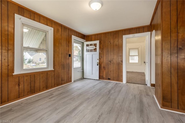 foyer entrance with baseboards, light wood-style flooring, and wood walls