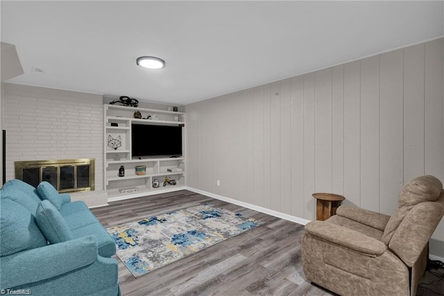 living room with a fireplace, baseboards, and wood finished floors