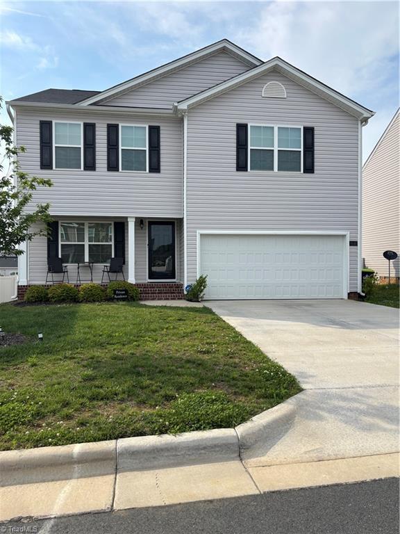 6849 Keeneland Dr, Whitsett, NC 27377 - view of front of home featuring an attached garage, a front yard, covered porch, and concrete driveway