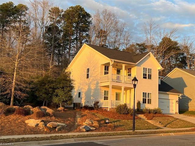 view of front of property featuring central AC, a balcony, and a garage