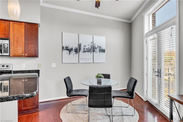 dining space with ornamental molding, dark wood-type flooring, a ceiling fan, and baseboards