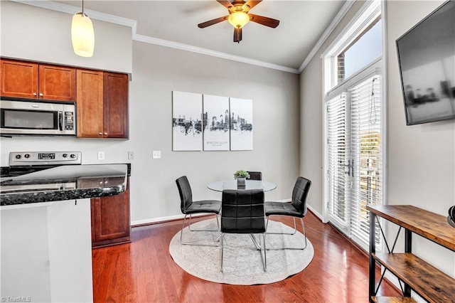 dining space featuring dark wood finished floors, crown molding, and baseboards