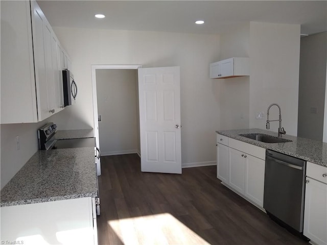 kitchen with appliances with stainless steel finishes, white cabinets, light stone counters, and sink