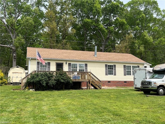 manufactured / mobile home with a deck, a front yard, and a storage shed