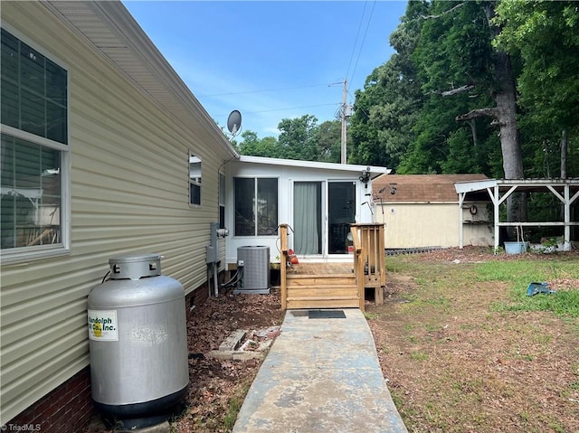 exterior space with central air condition unit, a storage unit, and a wooden deck