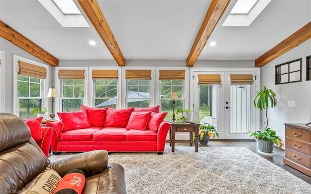 living room featuring french doors, beamed ceiling, and a skylight