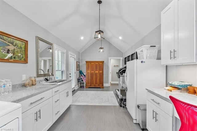 kitchen with white refrigerator, white cabinetry, sink, and pendant lighting