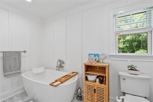 bathroom with a tub to relax in and toilet