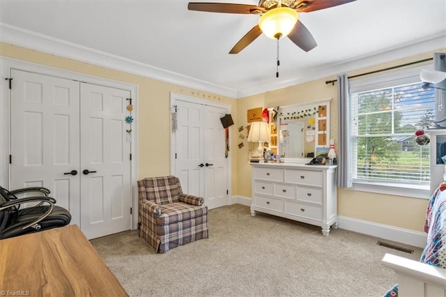 living area with crown molding, light colored carpet, and ceiling fan