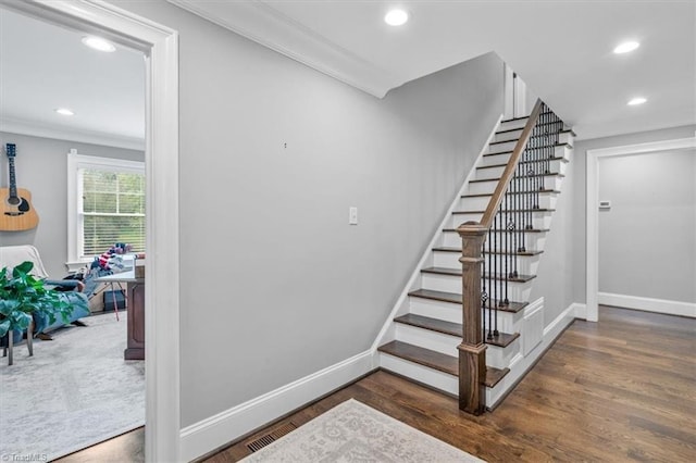 staircase with ornamental molding and wood-type flooring