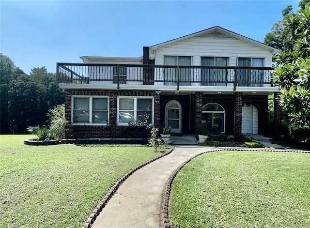 view of front facade with a balcony and a front yard